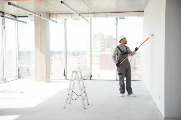 indian apartment repair worker paints white wall with roller